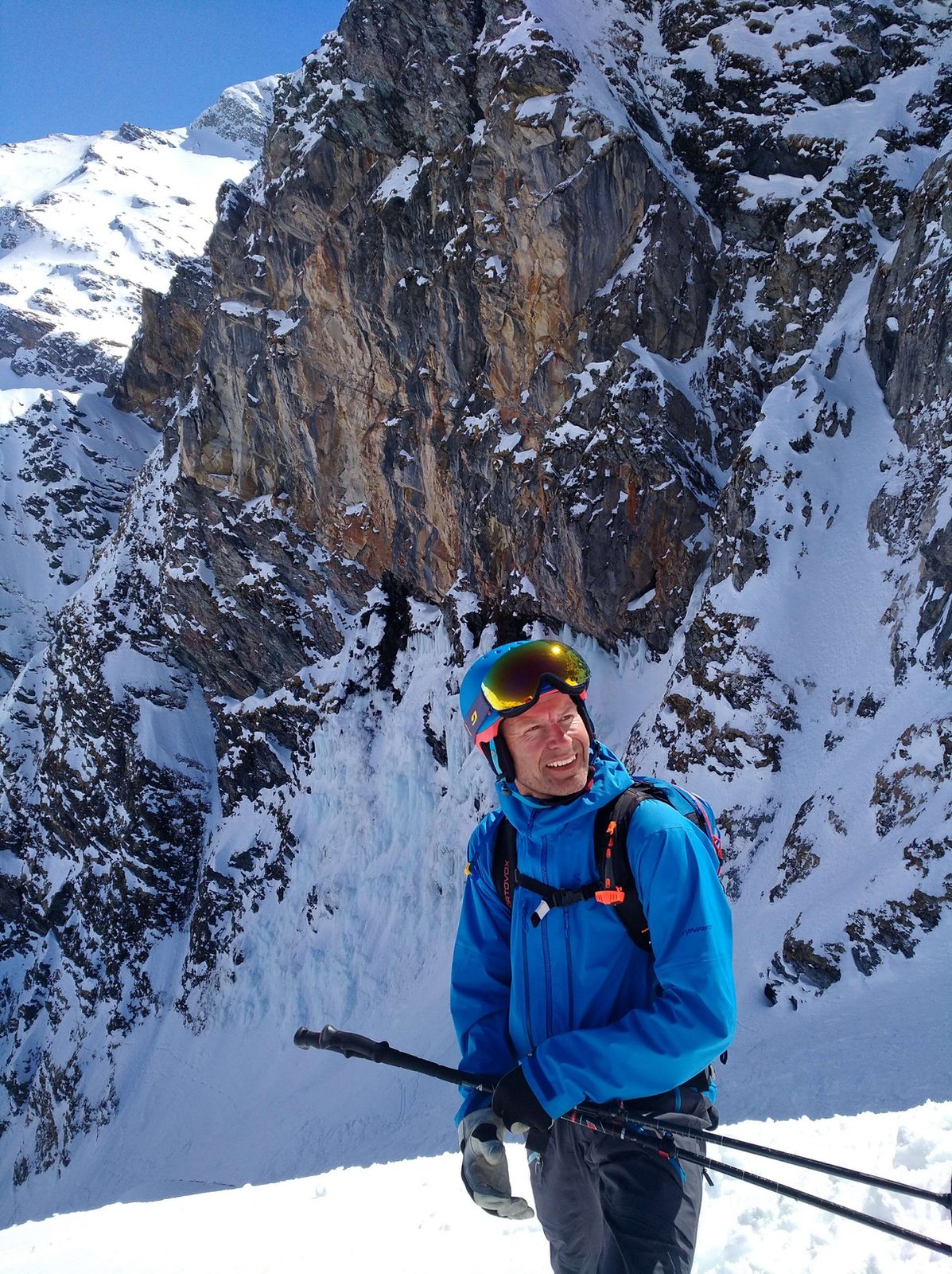 Harald Prey mit Helm und Skistoecken vor einer steilen vereisten Rinne